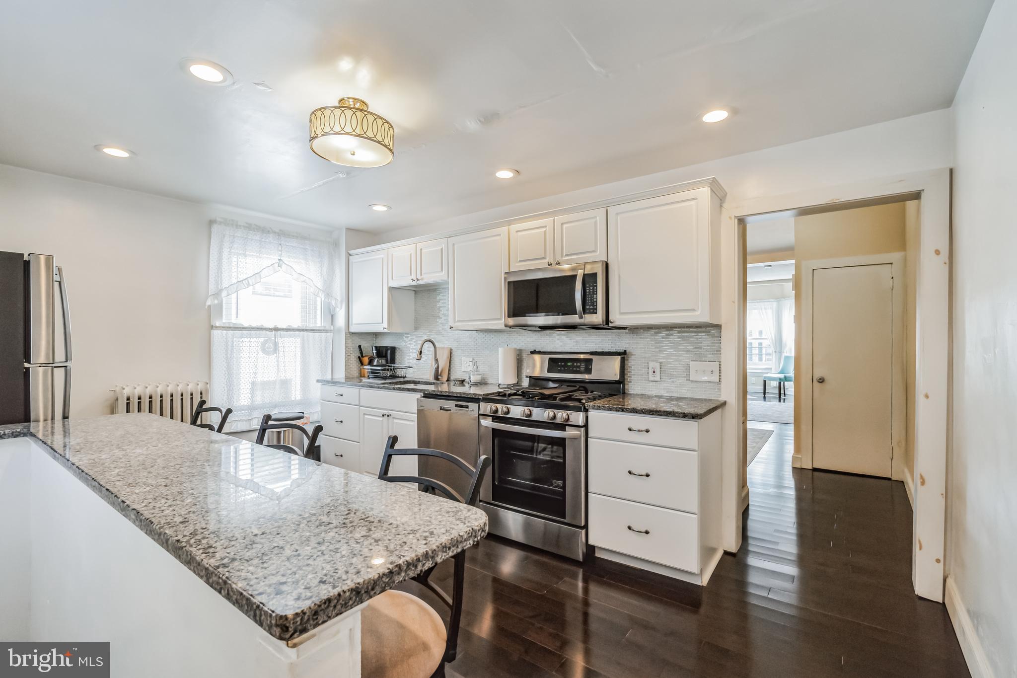 6774 Ridge Avenue, Unit 2 Philadelphia, PA 19128 - Photo 1 of 15 a kitchen with stainless steel appliances granite countertop a stove top oven a sink dishwasher and a refrigerator with wooden floor