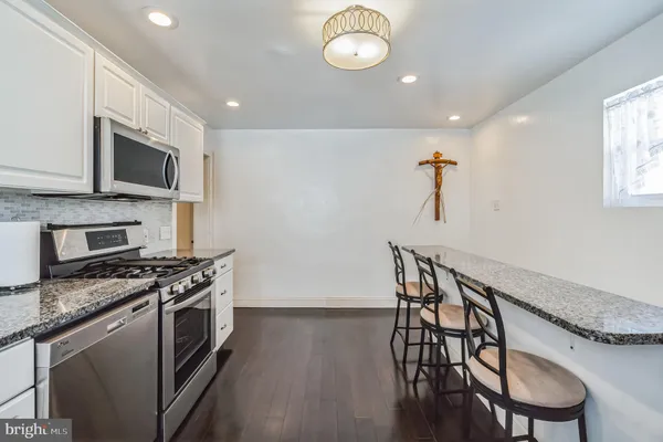 a kitchen with stainless steel appliances a table chairs microwave and stove top oven