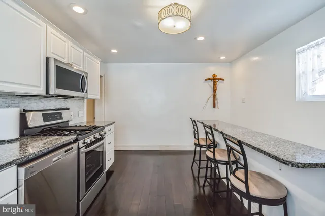 a kitchen with stainless steel appliances a table chairs microwave and stove top oven