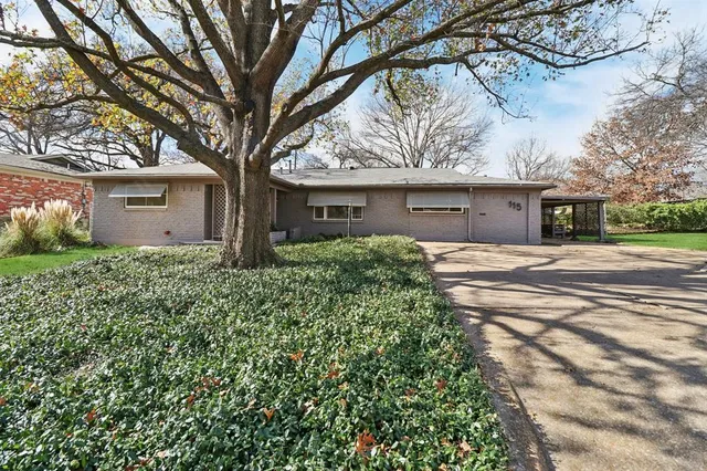 a front view of a house with a tree and a yard