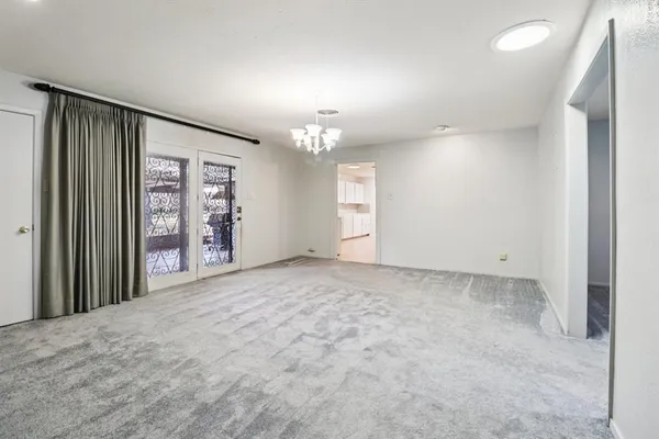 an empty room with windows and chandelier fan