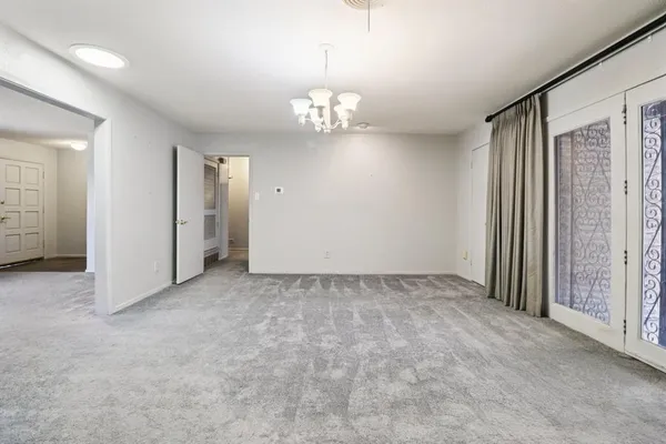an empty room with chandelier fan and windows