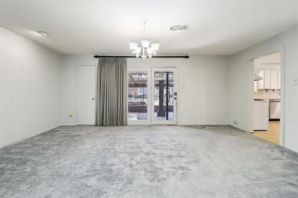 an empty room with chandelier fan and windows