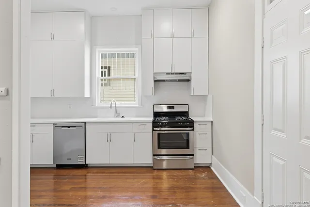 a kitchen with cabinets appliances and wooden floor