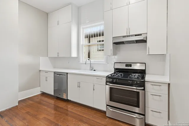 a kitchen with stainless steel appliances granite countertop a sink and a stove next to a window