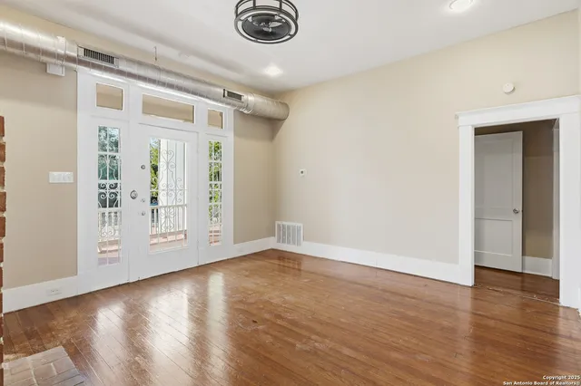 a view of an empty room with window and wooden floor