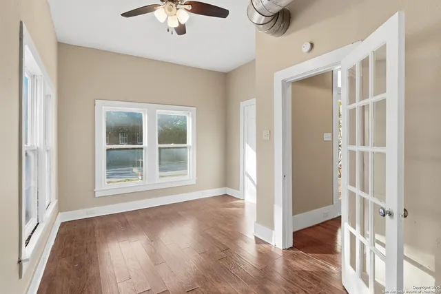 a view of an empty room with wooden floor and a window