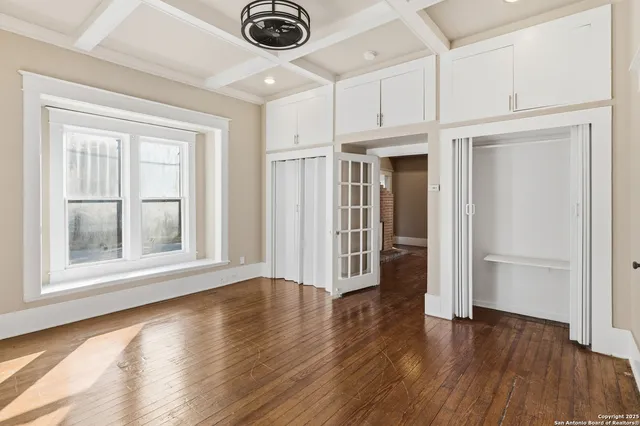 a view of an empty room with a window and wooden floor