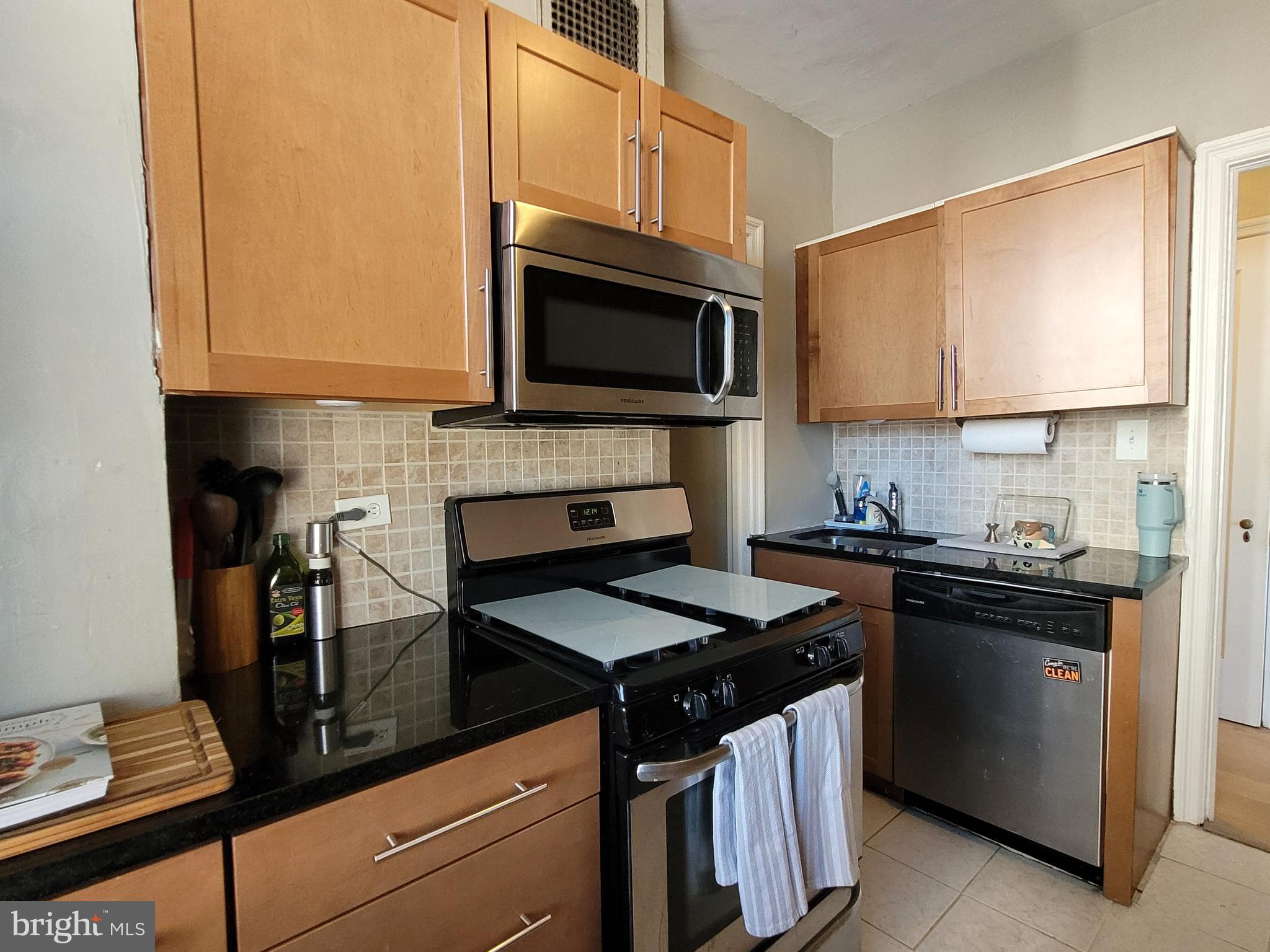 2031 Locust Street, Unit 802 Philadelphia, PA 19103 - Photo 6 of 26 a kitchen with granite countertop a stove top oven microwave and cabinets