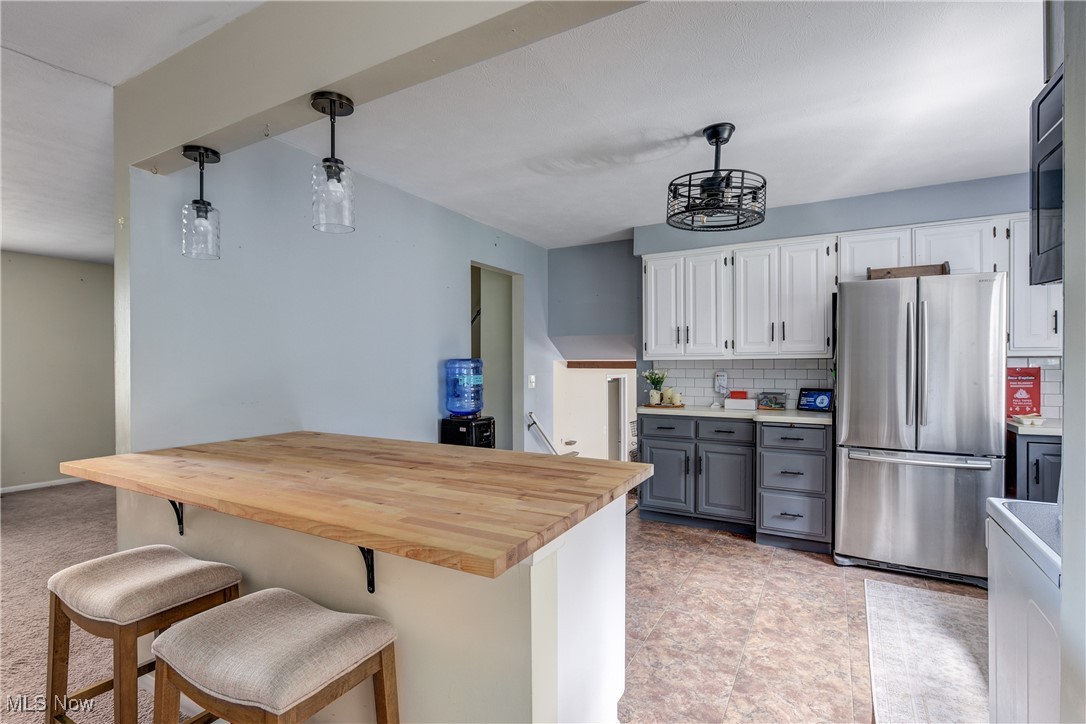 13765 Newton Road Cleveland, OH 44130 - Photo 11 of 42 Kitchen featuring freestanding refrigerator, hanging light fixtures, tasteful backsplash, gray cabinets, and white cabinetry