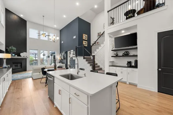 a large white kitchen with granite countertop a stove a sink a dining table and chairs with wooden floor