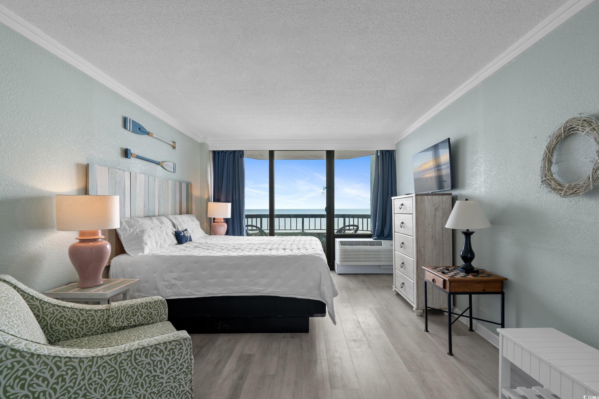 2401 South Ocean Boulevard, Unit 659 Myrtle Beach, SC 29577 - Photo 13 of 38 Bedroom with a textured wall, a textured ceiling, expansive windows, wood finished floors, and crown molding