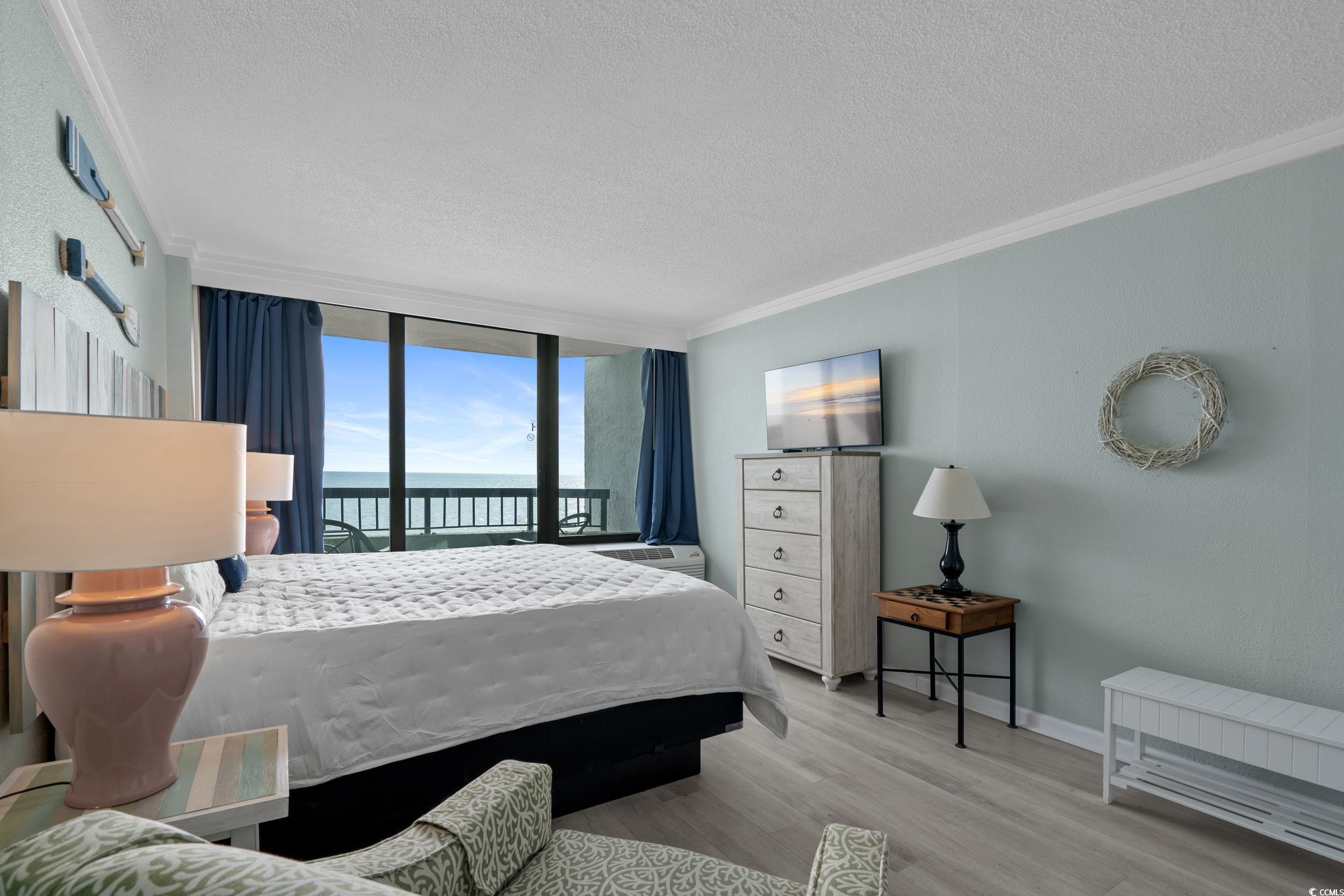 2401 South Ocean Boulevard, Unit 659 Myrtle Beach, SC 29577 - Photo 14 of 38 Bedroom with a textured ceiling, ornamental molding, access to outside, light wood-style flooring, and expansive windows