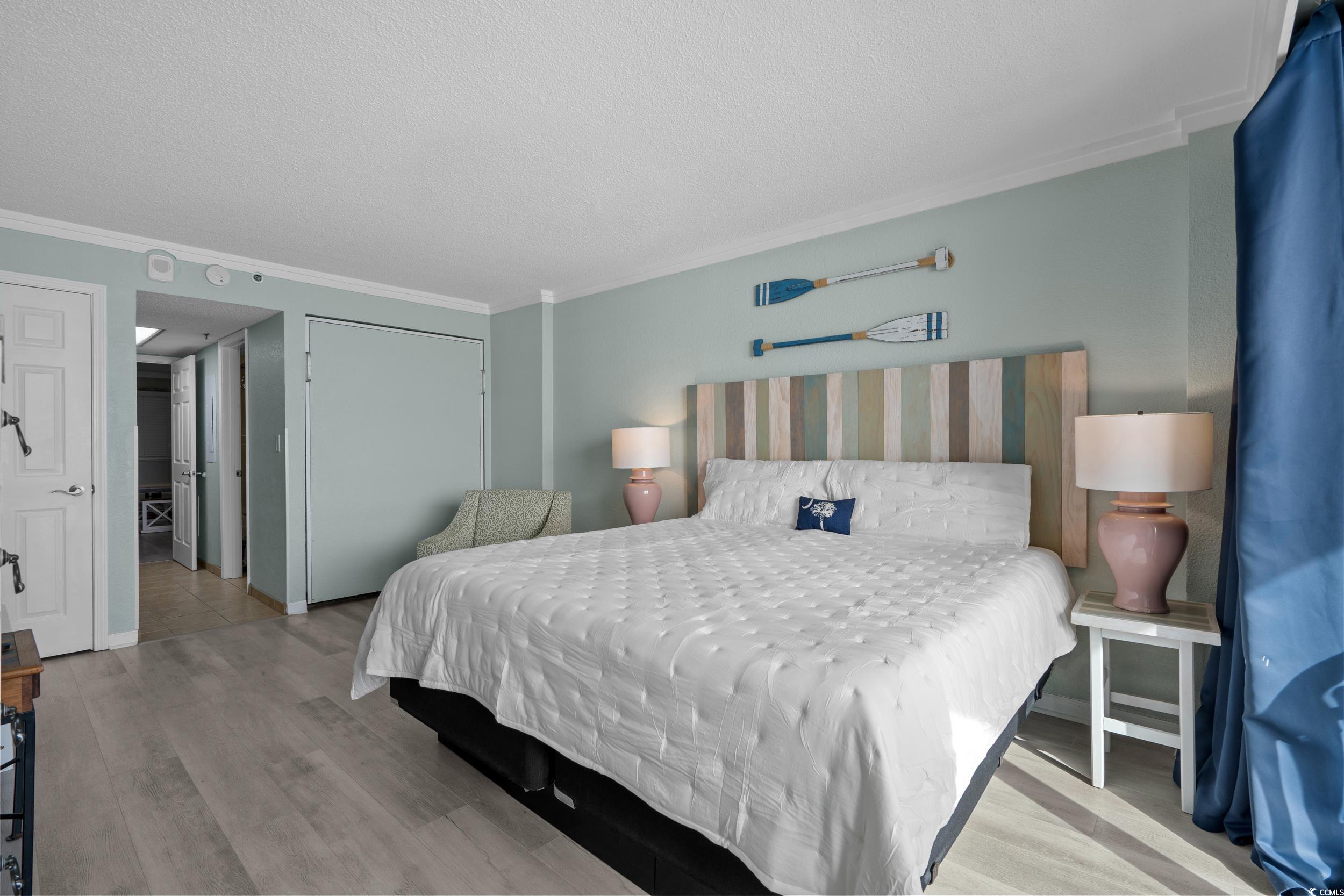 2401 South Ocean Boulevard, Unit 659 Myrtle Beach, SC 29577 - Photo 20 of 38 Bedroom featuring a textured ceiling, a closet, light wood-style floors, and ornamental molding