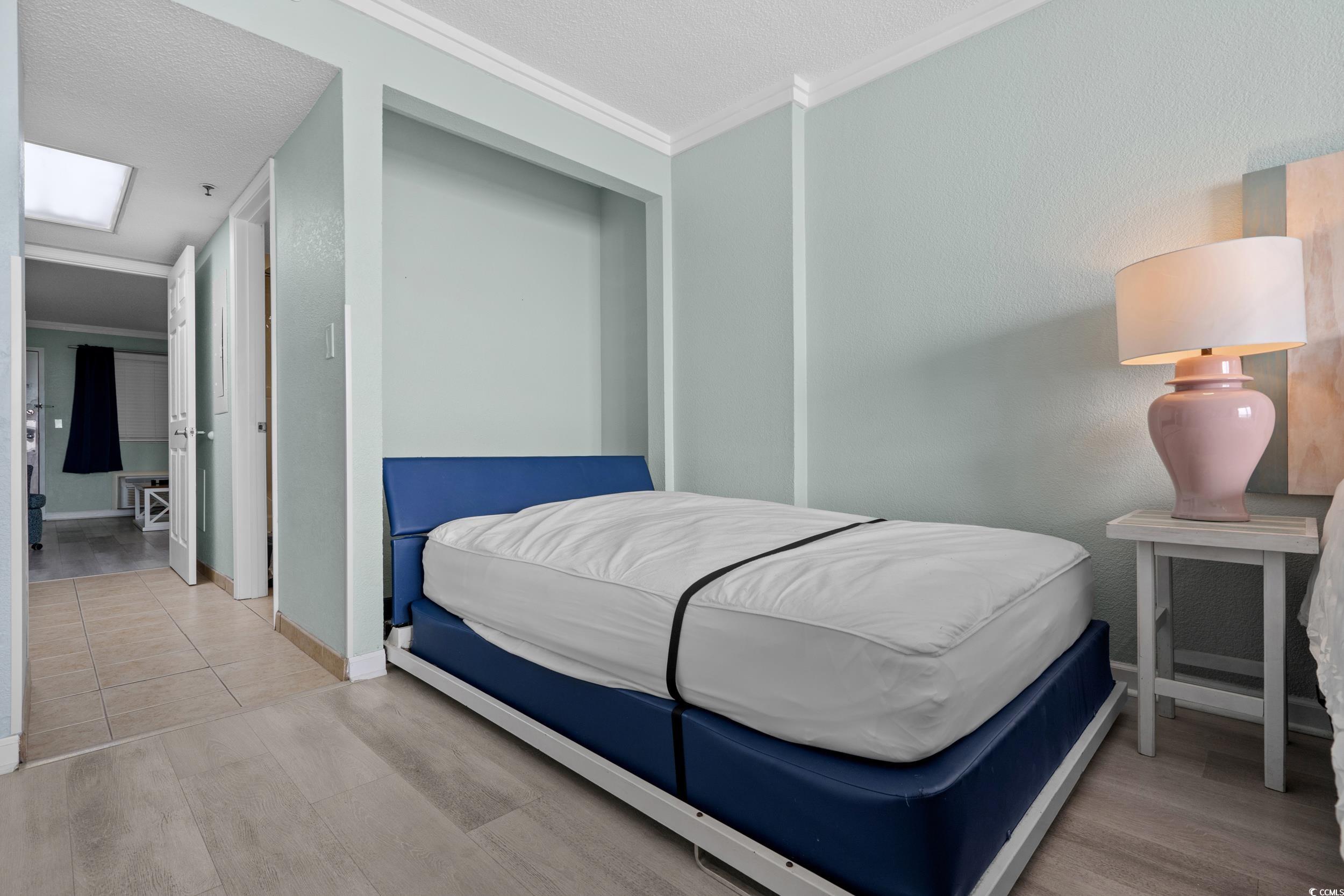 2401 South Ocean Boulevard, Unit 659 Myrtle Beach, SC 29577 - Photo 21 of 38 Bedroom featuring ornamental molding, light wood-type flooring, and a textured ceiling