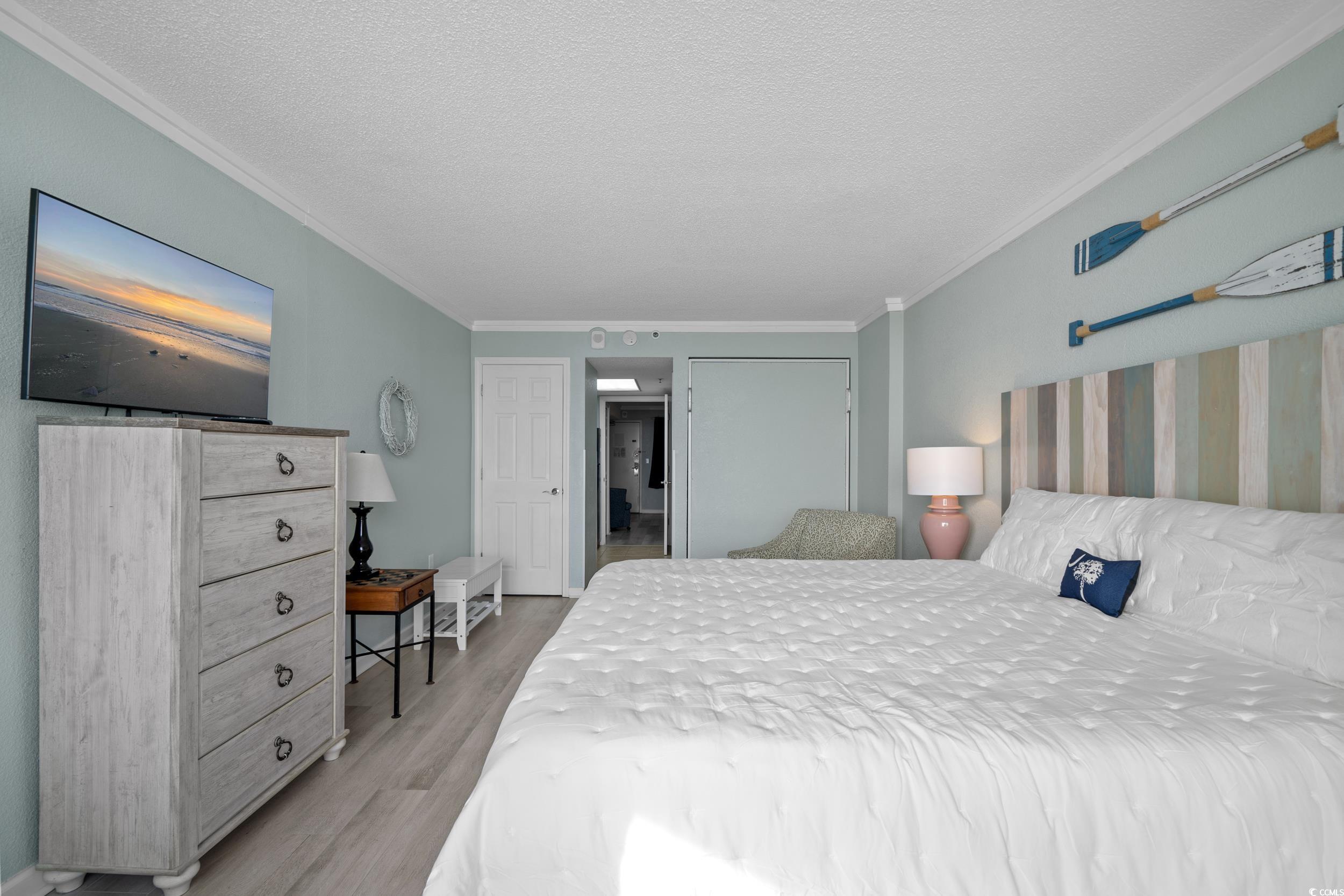 2401 South Ocean Boulevard, Unit 659 Myrtle Beach, SC 29577 - Photo 22 of 38 Bedroom with a textured ceiling, ornamental molding, light wood-type flooring, and a closet