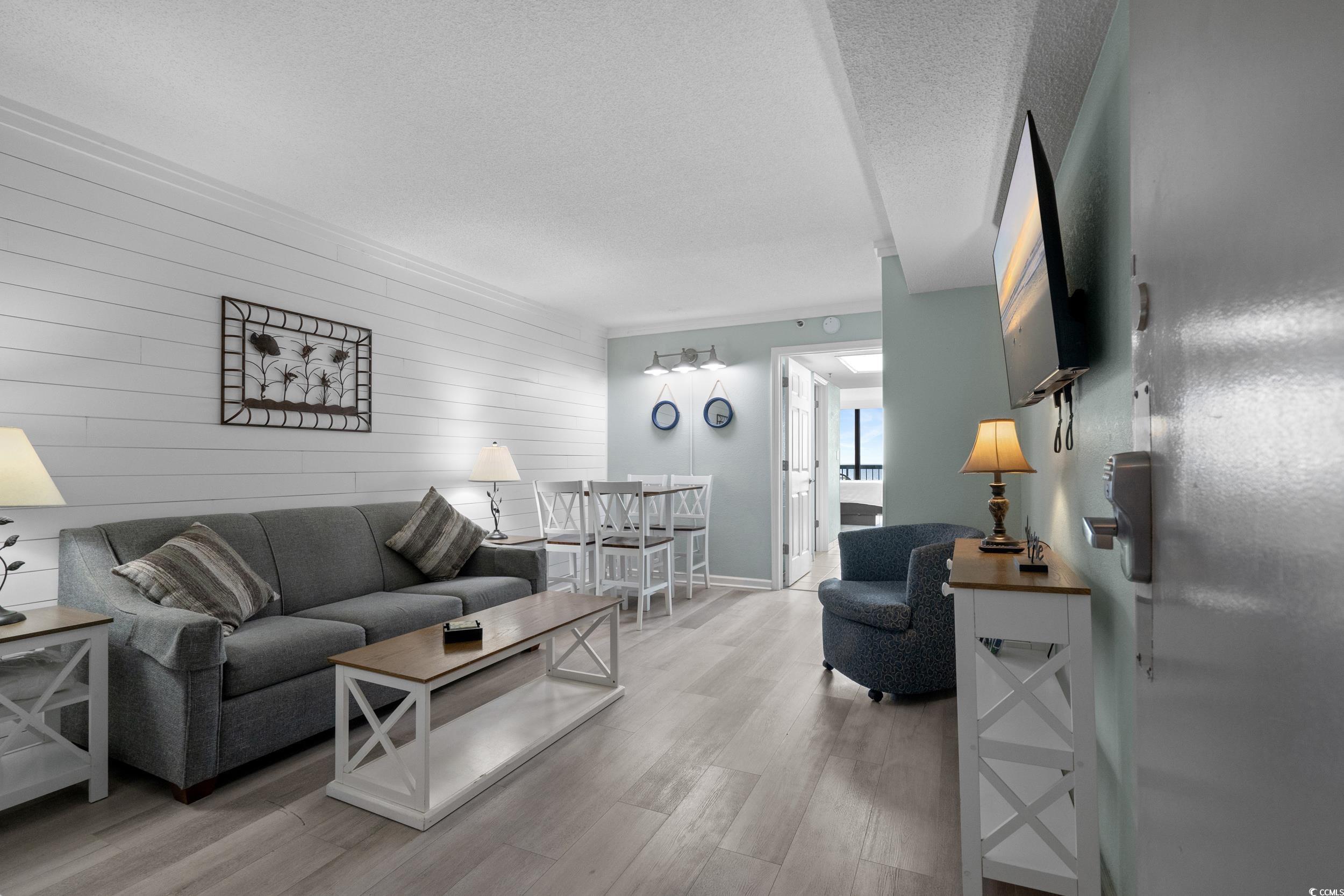 2401 South Ocean Boulevard, Unit 659 Myrtle Beach, SC 29577 - Photo 4 of 38 Living area featuring wooden walls, a textured ceiling, light wood finished floors, and an accent wall