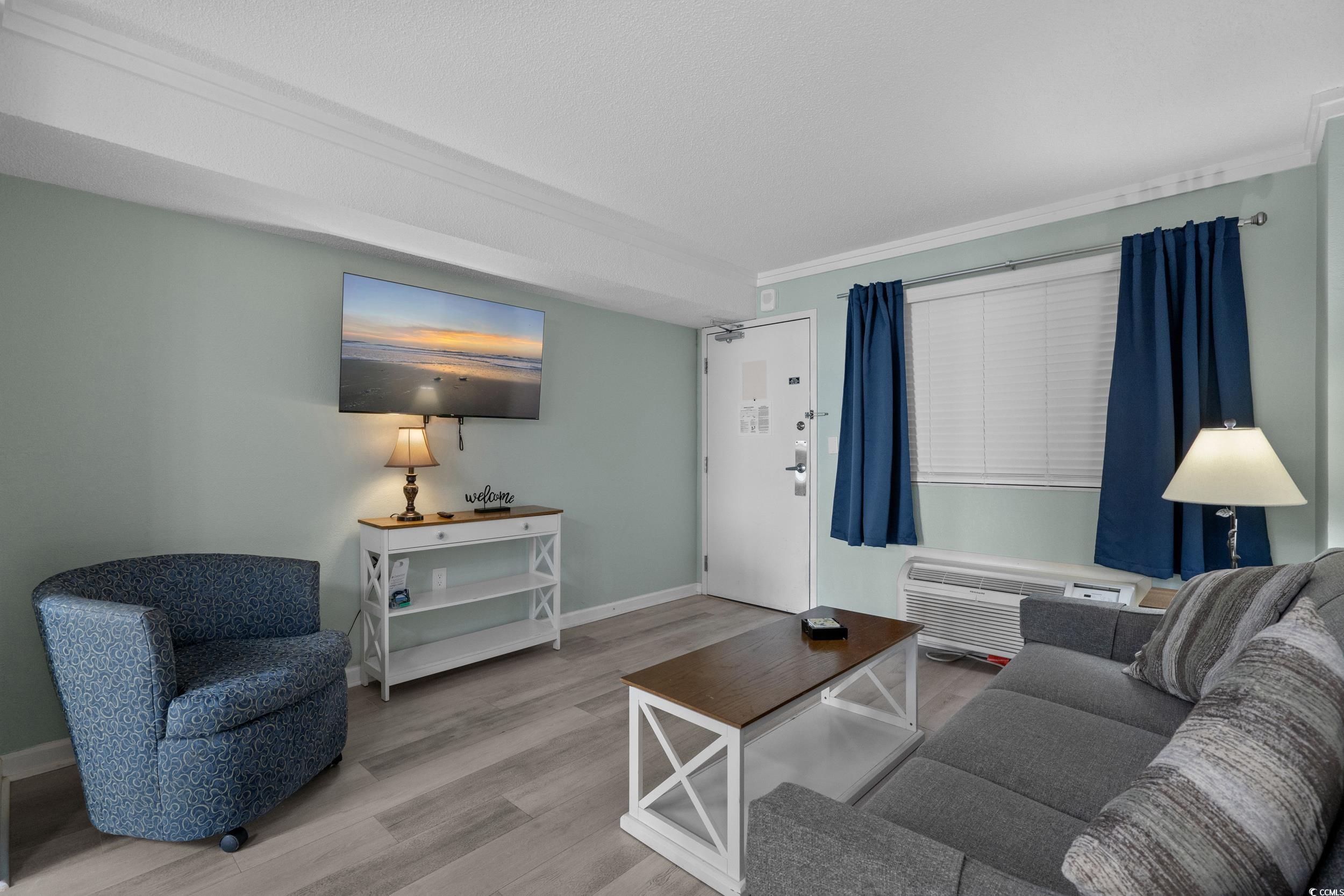 2401 South Ocean Boulevard, Unit 659 Myrtle Beach, SC 29577 - Photo 6 of 38 Living area with wood finished floors, ornamental molding, and a wall unit AC