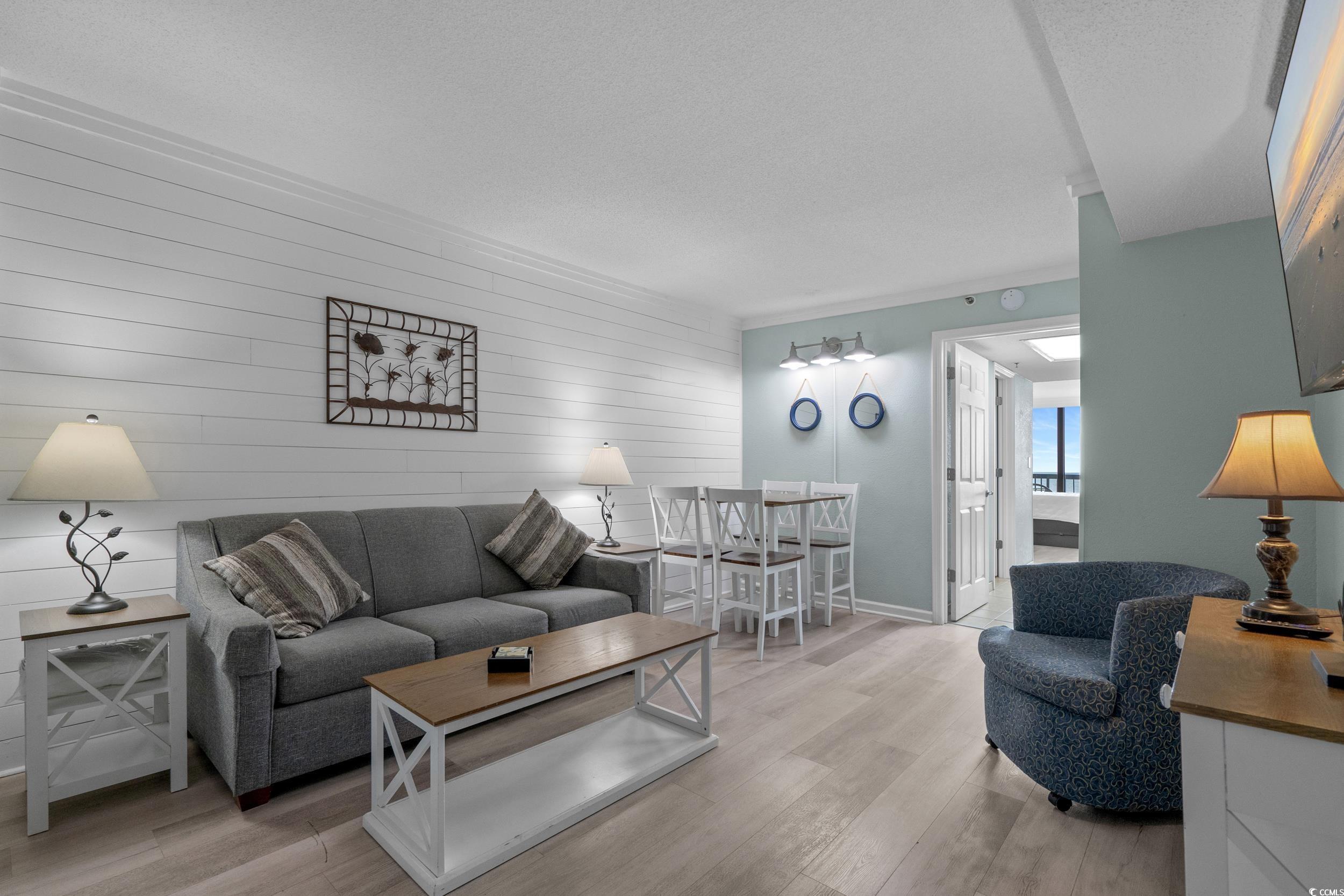 2401 South Ocean Boulevard, Unit 659 Myrtle Beach, SC 29577 - Photo 8 of 38 Living room with wooden walls, light wood-type flooring, a textured ceiling, and an accent wall