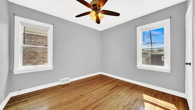 a view of empty room with wooden floor and fan