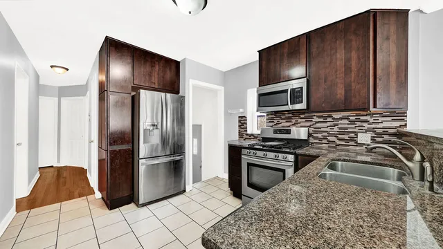 a kitchen with granite countertop a refrigerator stove and microwave