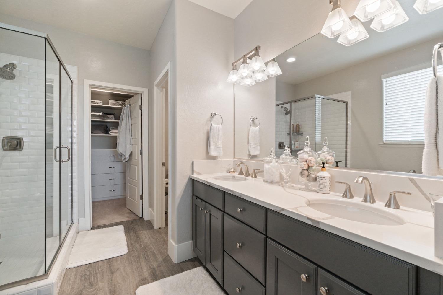 4491 Vineyard Drive Madera, CA 93636 - Photo 35 of 47 a en suite bathroom with a double vanity sink a large mirror a shower and a bathtub