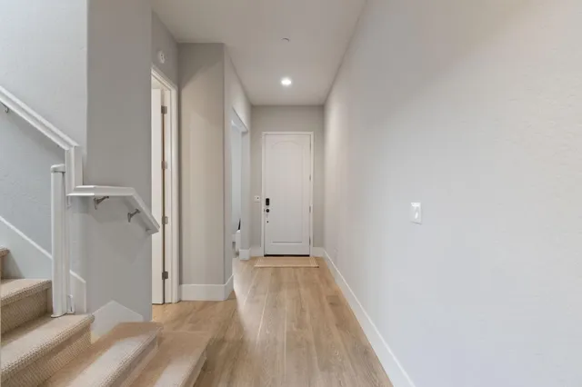 a view of a hallway with wooden floor and a bathroom