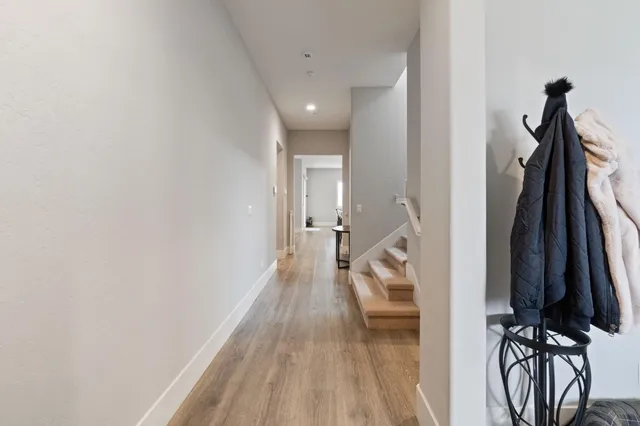 a view of a hallway with wooden floor and a bathroom