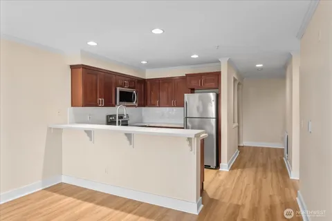 a kitchen with stainless steel appliances granite countertop a refrigerator sink and wooden cabinets