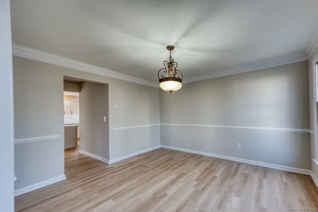 an empty room with wooden floor and chandelier