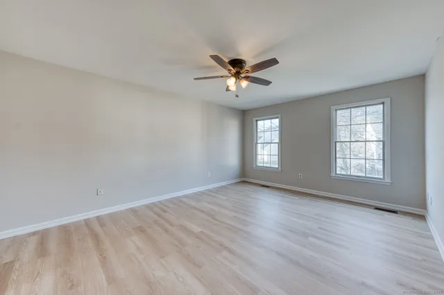 an empty room with wooden floor and windows