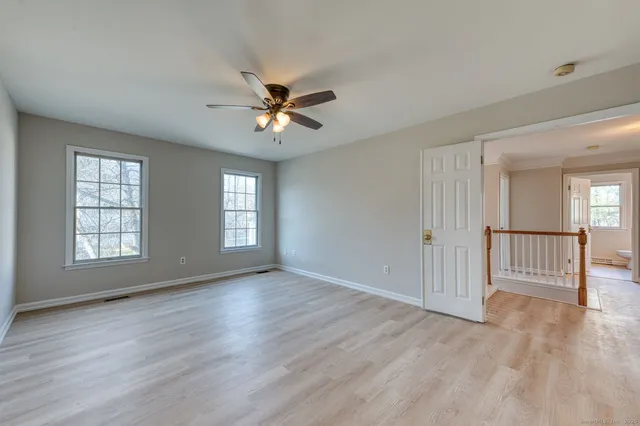 a view of empty room with wooden floor and fan