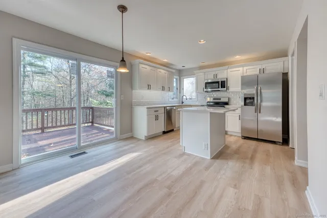 a kitchen with stainless steel appliances granite countertop a refrigerator a sink dishwasher a stove and white countertops with wooden floor