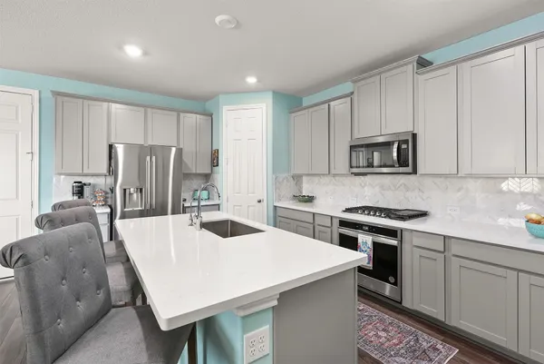 a kitchen with stainless steel appliances a stove a sink a microwave a refrigerator a center island and a refrigerator