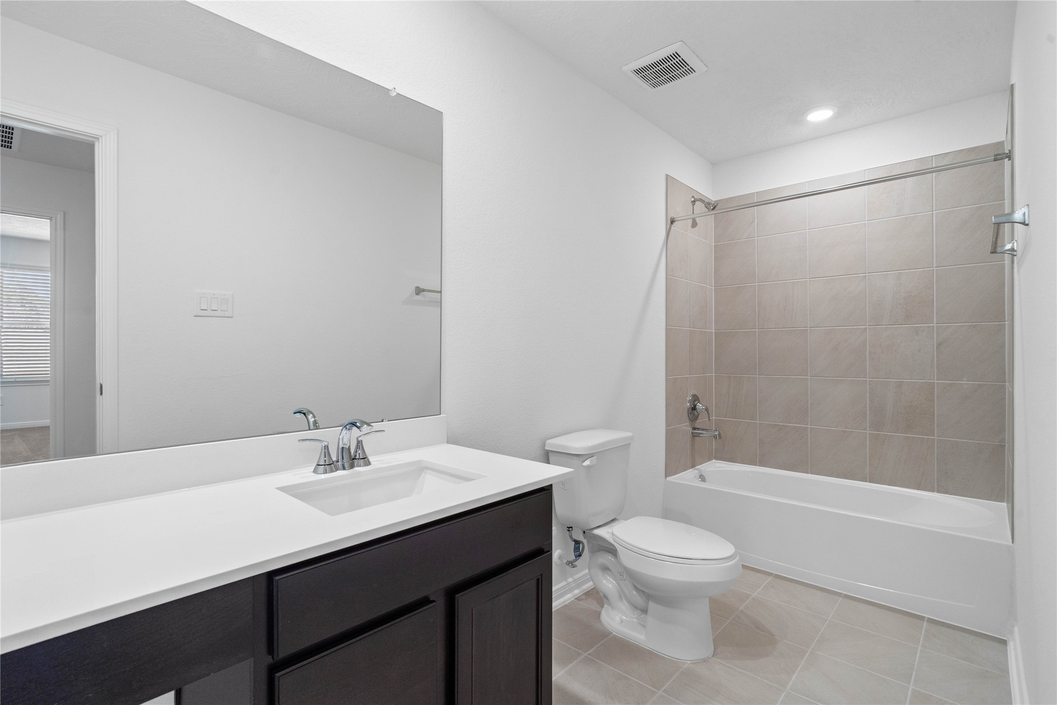 25503 Alpine Switchback Drive Spring, TX 77373 - Photo 23 of 32 The secondary bathroom showcases tile flooring, a bath/shower combo with Daltile tile surround, a vanity with knee space and stunning light countertop, a mirror, sleek fixtures, and contemporary finishes throughout.