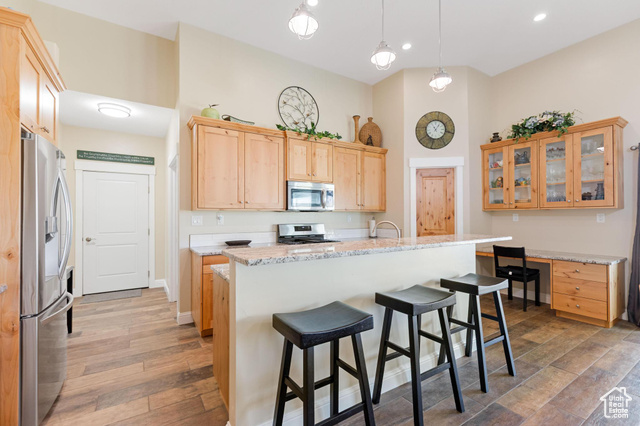 19502 South Olson Road Downey, ID 83234 - Photo 16 of 64 Kitchen featuring appliances with stainless steel finishes, a breakfast bar, hanging light fixtures, light brown cabinetry, and dark wood-style floors