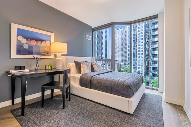 a bedroom with a bed lamp and a large window