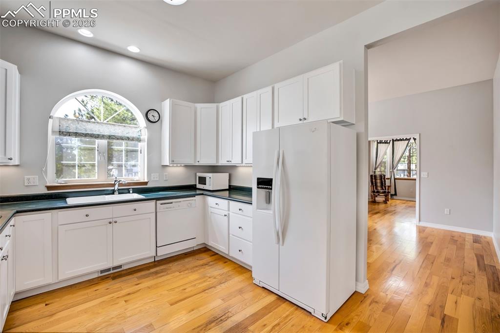 18554 Wetherill Road Monument, CO 80132 - Photo 12 of 50 a kitchen with granite countertop a refrigerator a sink dishwasher a stove and white countertops with wooden floor