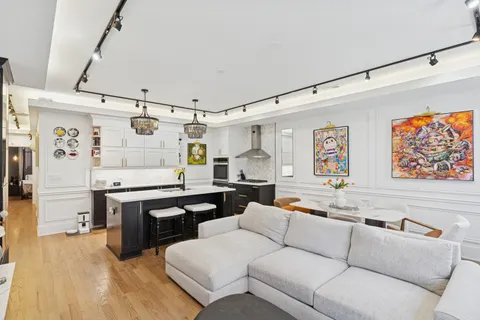 a living room with stainless steel appliances furniture and a kitchen view
