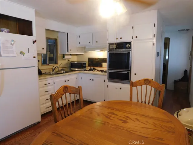 a kitchen with a refrigerator a stove a sink a dining table and chairs