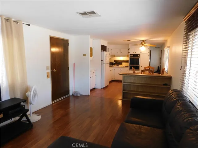 a living room with stainless steel appliances furniture and a wooden floor