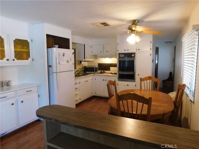 a kitchen with stainless steel appliances granite countertop a refrigerator a stove top oven a sink dishwasher and white cabinets with wooden floor