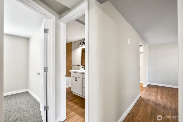 a view of a hallway with wooden floor and a bathroom