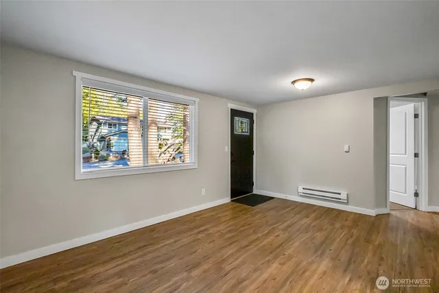 a view of an empty room with wooden floor and a window