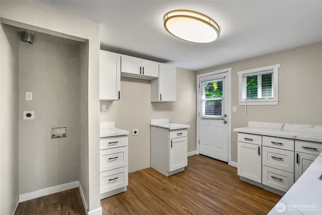 a kitchen with white cabinets and wooden floor