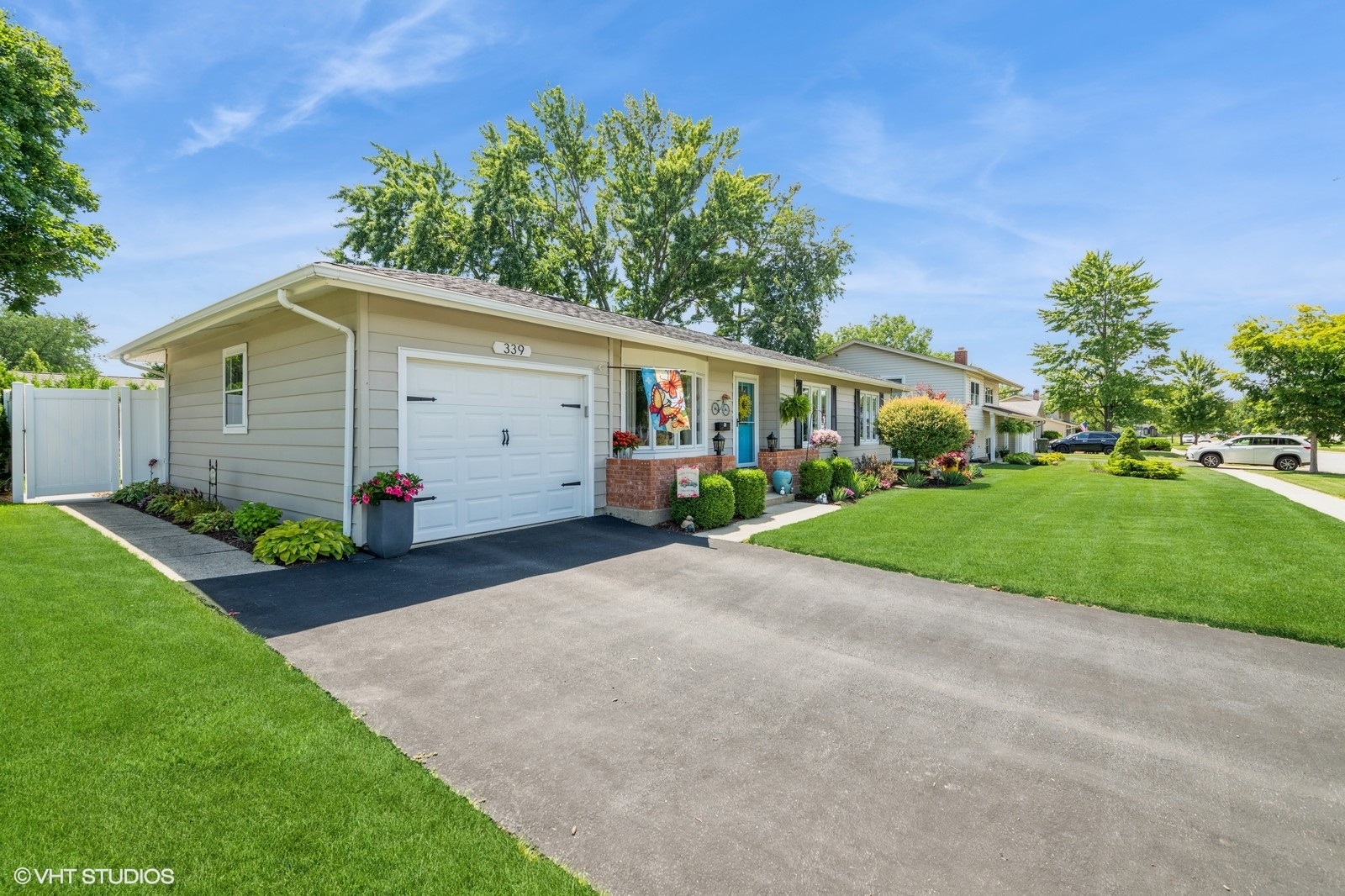 339 Yarmouth Road Elk Grove Village, IL 60007 - Photo 4 of 40 a view of a white house with a yard plants and large tree