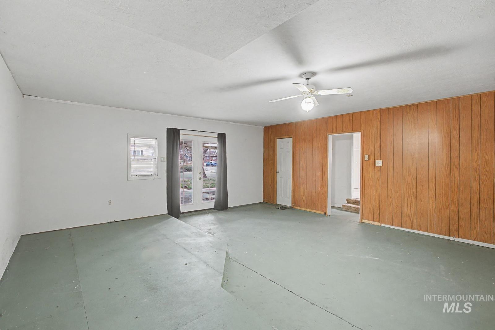 918 Elm Street Clarkston, WA 99403 - Photo 23 of 35 Unfurnished room featuring wood walls, concrete floors, ceiling fan, and french doors