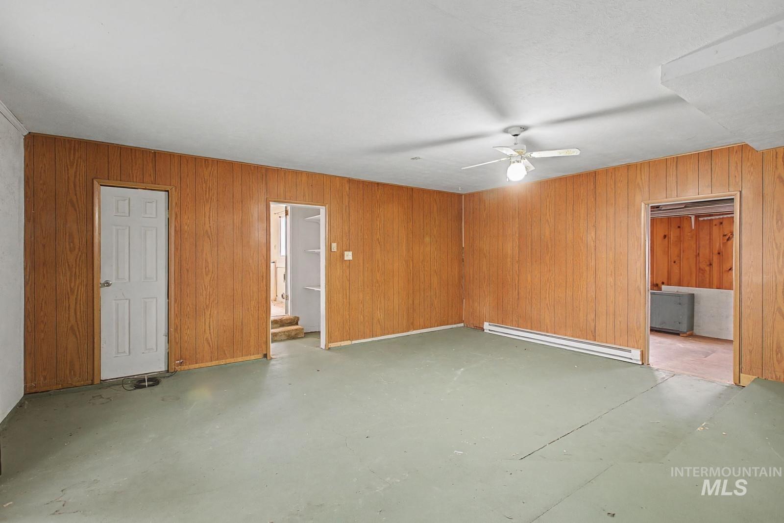 918 Elm Street Clarkston, WA 99403 - Photo 24 of 35 Empty room featuring concrete flooring, baseboard heating, a ceiling fan, and wood walls