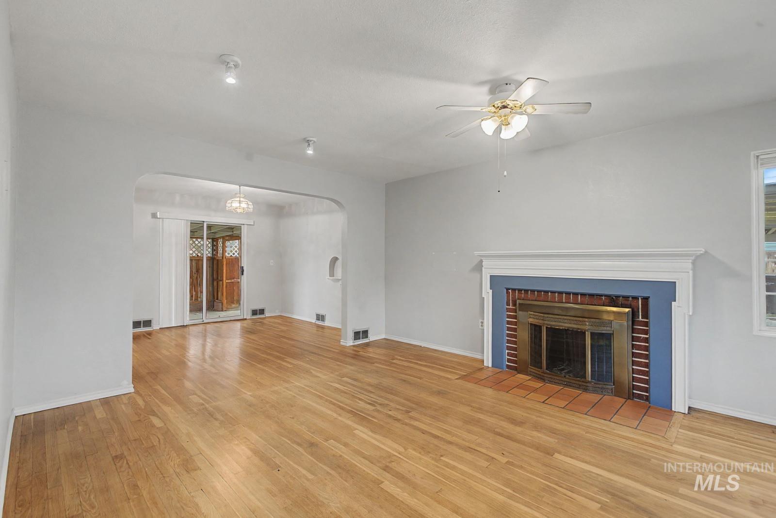 918 Elm Street Clarkston, WA 99403 - Photo 4 of 35 Unfurnished living room featuring ceiling fan, arched walkways, light wood finished floors, and a fireplace