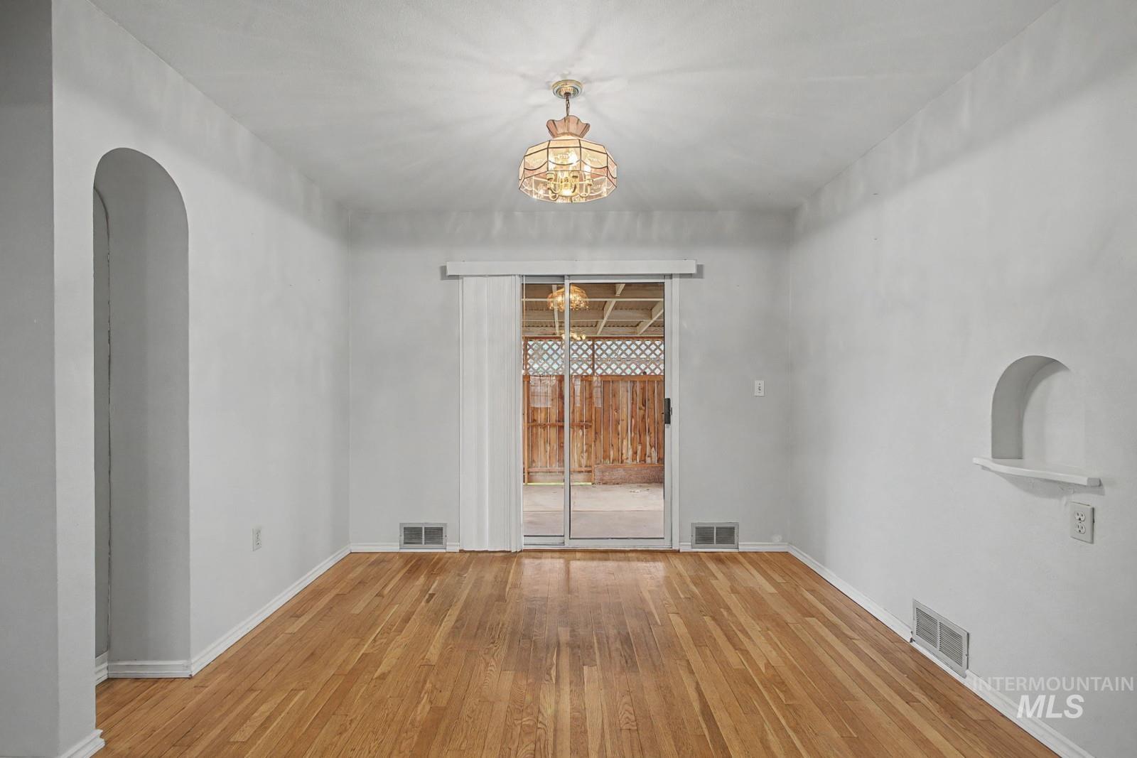 918 Elm Street Clarkston, WA 99403 - Photo 7 of 35 Unfurnished room featuring hardwood / wood-style flooring, hanging lights, and arched walkways